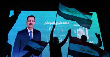 Supporters of incumbent Iraqi Prime Minister Mohammed S. Al Sudani wave national flags in front of a screen displaying his portrait as they celebrate following the announcement of preliminary election results, Baghdad, Iraq, Nov. 12, 2025. (AFP Photo)