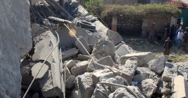 People stand in front of a damaged house that the Afghan Taliban government claims was damaged in Pakistani airstrikes, in Asadabad, Kunar province, Afghanistan, Nov. 25, 2025. (Reuters Photo)