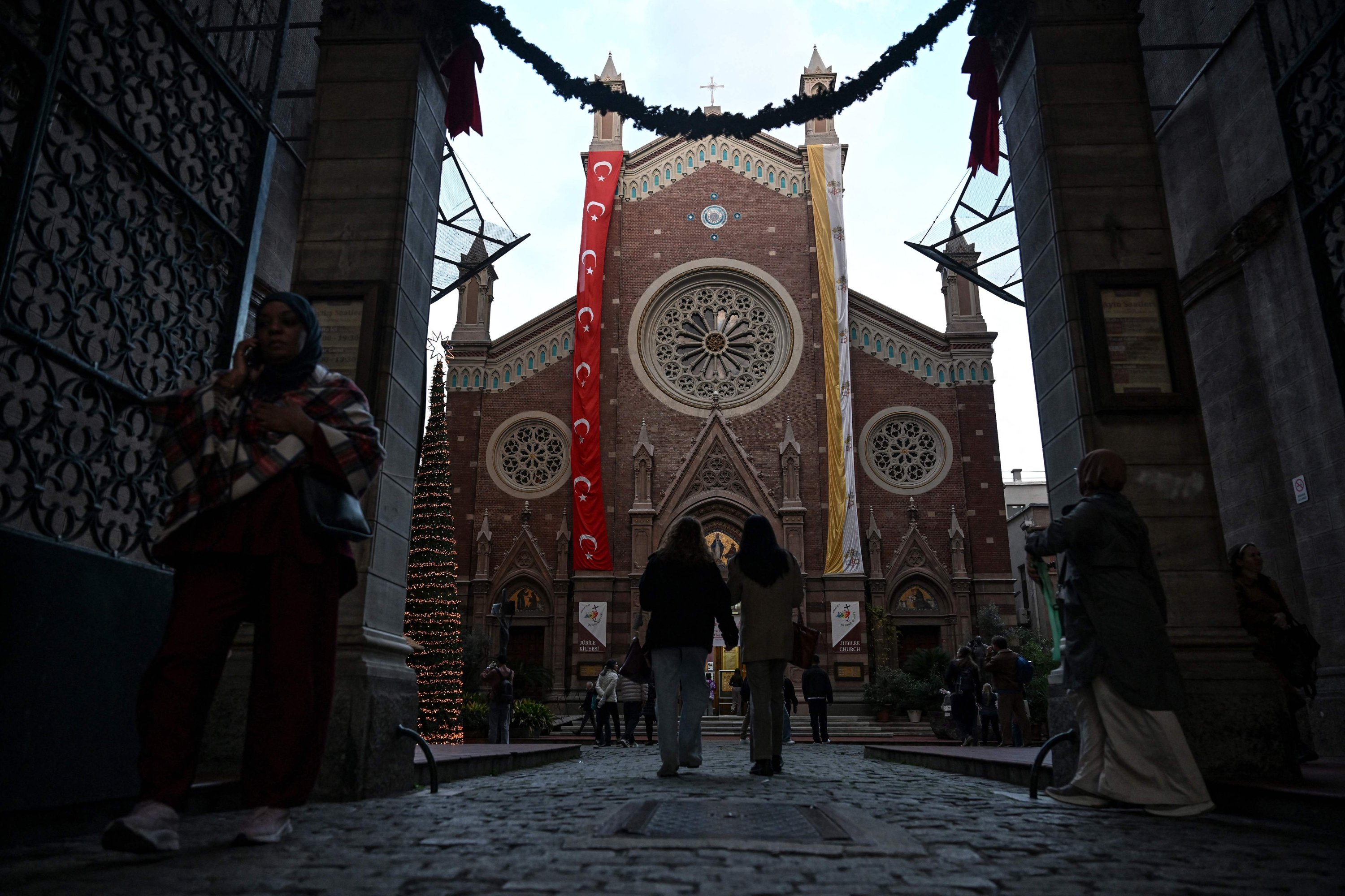 People walk outside the Saint Anthony of Padua Church ahead of Pope Leo XIV's visit, Istanbul, Türkiye, Nov. 24, 2025. (AFP Photo)