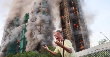 A man reacts as smoke rises while flames engulf bamboo scaffolding across multiple buildings at Wang Fuk Court housing estate, in Tai Po, Hong Kong, China, Nov. 26, 2025. (Reuters Photo)
