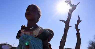 A Sudanese refugee girl from al-Fashir carries her brother and walks at the Tine transit refugee camp, in eastern Chad, Nov. 23, 2025. (Reuters Photo)