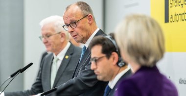 German Chancellor Friedrich Merz (2nd L) speaks near Minister President of Baden-Wuerttemberg Winfried Kretschmann (L) and Stephane Sejourne, Executive Vice-President of the European Commission for Prosperity and Industrial Strategy (2nd R) duuring the Strategic Dialogue on Automotive Industry in Baden-Wuerttemberg at the Stuttgart trade fair grounds, Stuttgart, Germany, Nov. 26, 2025. (AFP Photo)