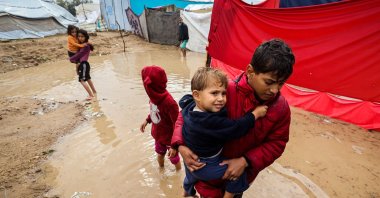 Palestinian children walk in flood water after heavy rain at a makeshift camp housing displaced Palestinians in Maghazi refugee camp in the central Gaza Strip, Nov. 25, 2025. (AFP Photo)