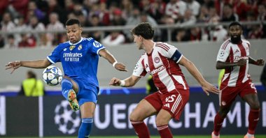 Real Madrid&#039;s Kylian Mbappe (L) fights for the ball with Olympiakos&#039; Panagiotis Retsos (C) during the UEFA Champions League, league phase - matchday 5, football match at the Georgios Karaiskakis Stadium, Piraeus, Greece, Nov. 26, 2025. (AFP Photo)