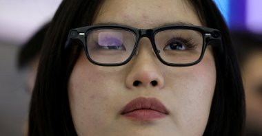 A woman tries on a pair of Quark AI glasses by Alibaba at the company&#039;s booth at the expo of the World Internet Conference, Zhejiang, China, Nov. 8, 2025. (Reuters Photo)
