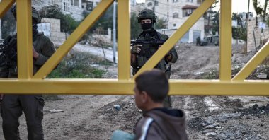 Israeli soldiers stand guard behind a barrier as a Palestinian child looks on during an Israeli army raid on the outskirts of the Jenin refugee camp in the occupied West Bank, Nov. 27, 2025. (AFP Photo)
