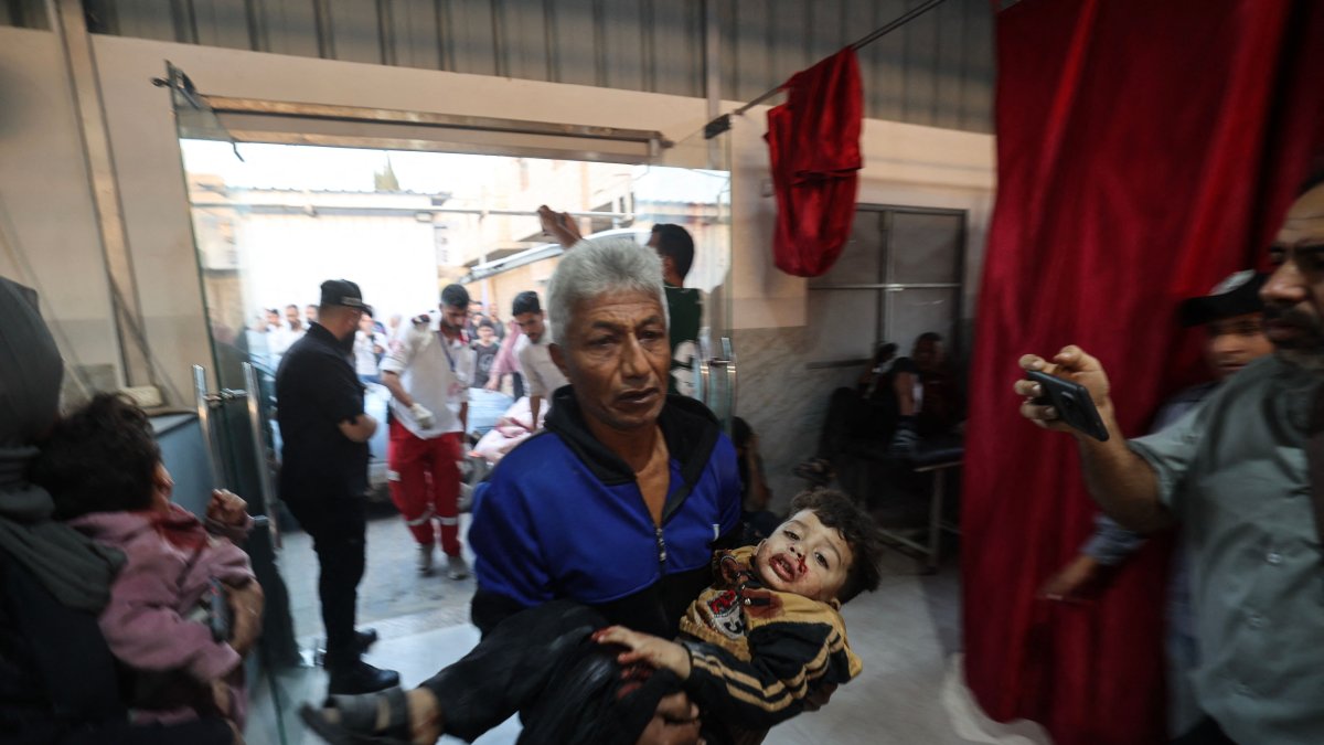  A Palestinian man carries an injured child at Al-Awda Hospital at the Nuseirat refugee camp in the central Gaza Strip, following Israeli strikes despite the cease-fire, Nov. 22, 2025. (AFP Photo)
