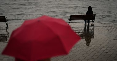 A woman sits on a bench by the Bosporus on a rainy day in Istanbul, Türkiye, Oct. 3, 2025. (AP Photo)