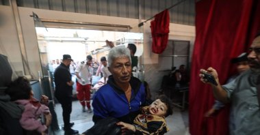  A Palestinian man carries an injured child at Al-Awda Hospital at the Nuseirat refugee camp in the central Gaza Strip, following Israeli strikes despite the cease-fire, Nov. 22, 2025. (AFP Photo)