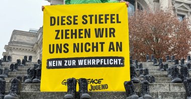 Knob cup army boots sit on the steps next to a banner reading "We are not putting on these boots – No to compulsory military service," during a Greenpeace Youth protest against plans to reintroduce compulsory military service, in front of the Bundestag, Berlin, Germany, Nov. 10, 2025. (Reuters Photo)