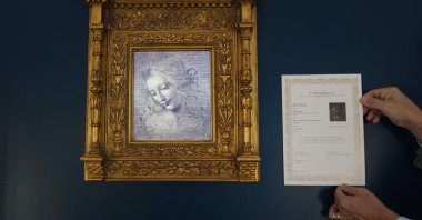 Primo Maronati holds a certificate next to a digital version of Leonardo Da Vinci&#039;s portrait, &quot;La Scapiliata, Lady with Disheveled Hair,&quot; at the Brera Art Gallery in Milan, Italy, Nov. 24, 2025. (AP Photo)