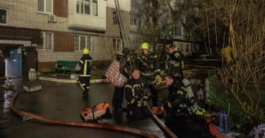 Firefighters take a break as smoke rises from a residential building that was set ablaze following a Russian drone attack on the city of Vyshhorod, in the Kyiv region, Ukraine, Nov. 30, 2025. (AFP Photo)