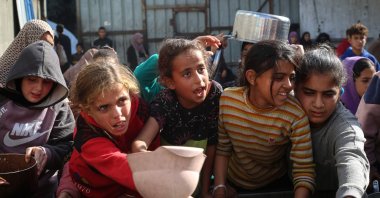 Displaced Palestinian children wait for a food portion at a shelter where families have been living, in Nuseirat, central Gaza Strip, Palestine, Nov. 23, 2025. (AFP Photo)