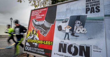 Voting posters in favor and against an initiative to tax the super-rich to help to finance the country&#039;s effort against climate change is seen in a street in Geneva, Switzerland, Nov. 25, 2025. (AFP Photo)