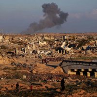 People walk amid the rubble of destroyed buildings at the Nuseirat camp for displaced Palestinians as smoke billows in the distance following Israeli strikes east of Gaza City, Dec. 2, 2025. (AFP Photo)