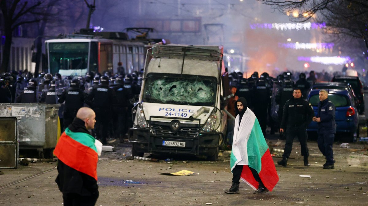 Police stand in formation as protesters walk covered by Bulgarian flags during a rally against austerity measures in next year's draft budget, in Sofia, Monday, Dec 1, 2025. (AP Photo)