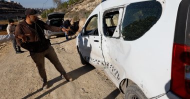 People point at a damaged vehicle, after Israeli forces shot and killed its 17-year-old driver, in Hebron, in the Israeli-occupied West Bank, Dec. 2, 2025. (Reuters Photo)