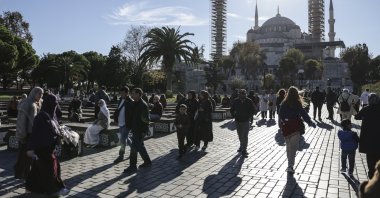 People walk in the historic Fatih district with the iconic Sultahmet Mosque, or Blue Mosque, in the background, Istanbul, Türkiye, Nov. 25, 2025. (EPA Photo) 