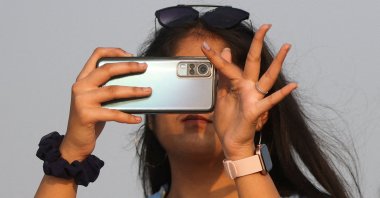 A woman uses a smartphone on a beach, Mumbai, India, Jan. 4, 2023. (Reuters Photo)