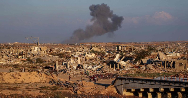People walk amid the rubble of destroyed buildings at the Nuseirat camp for displaced Palestinians as smoke billows in the distance following Israeli strikes east of Gaza City, Dec. 2, 2025. (AFP Photo)