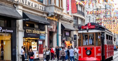 People walk next to the famed red tram on Istiklal Avenue, Istanbul, Türkiye, June 20, 2023. (Shutterstock Photo)