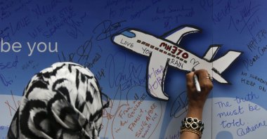 A woman writes messages for the passengers of missing Malaysia Airlines flight MH370 on a banner during a remembrance ceremony to mark the second anniversary of the plane&#039;s disappearance, in Kuala Lumpur, Malaysia, March 6, 2016. (EPA Photo)