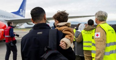 A Gazan man carries his son after landing at Geneva Airport, in Geneva, Switzerland, Nov. 28, 2025. (Reuters Photo)