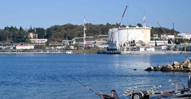 A fisherman fishes on the Black Sea coast in front of the entrance of Lukoil, near the city of Burgas, Bulgaria, Nov. 14, 2025. (AFP Photo)