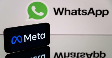 This photograph shows a smartphone and a computer screen displaying the logos of the WhatsApp app and its parent company Meta, Toulouse, France, Jan. 12, 2023. (AFP Photo)