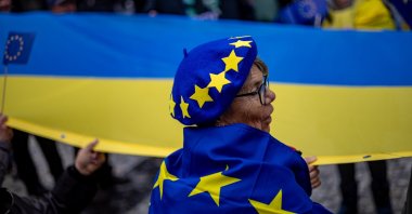 A woman a hat and flag with the EU symbols stands in front of a large Ukrainian flag in Prague, Czech Republic, Nov. 17, 2025. (EPA Photo)