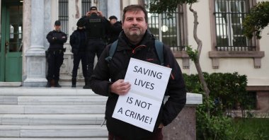 A person holds a placard prior to the trial of 24 aid workers involved in refugee rescues, at the town of Mytilene, on the island of Lesbos, Greece, Dec. 4, 2025. (Reuters Photo)