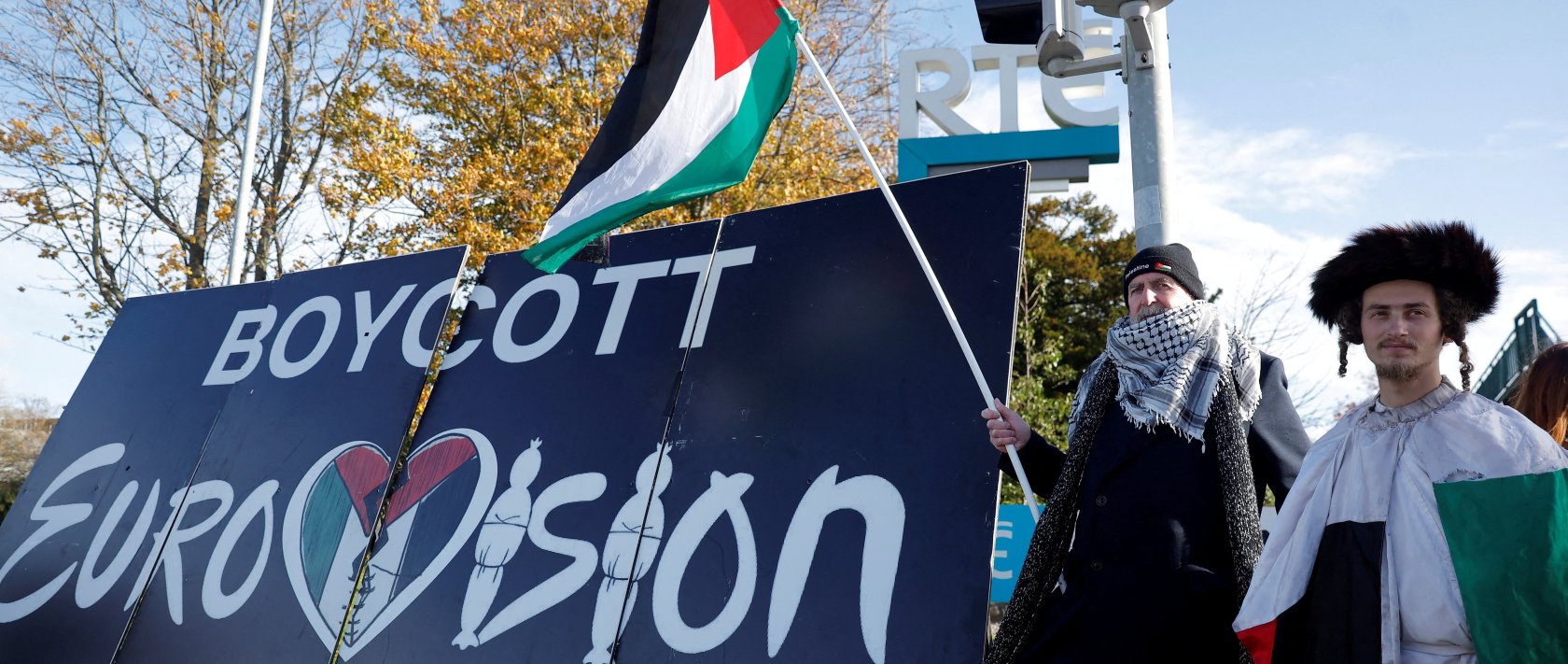 Pro-Palestinian protestors hold a flag and a banner outside the RTE (Radio Telefis Eireann) Irish public service broadcaster television studios as demonstrators call for an Irish boycott of the 2026 Eurovision Song Contest if there is Israeli participation, in Dublin, Ireland, Nov. 1, 2025. (Reuters File Photo)
