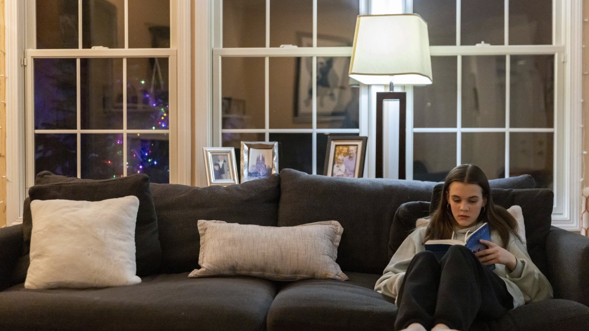 Teenager Sutton Bulkeley reads the novel &#039;Mockingjay&#039; by Suzanne Collins in the living room, in Westport, Connecticut, U.S., Feb. 16, 2024. (AP Photo)