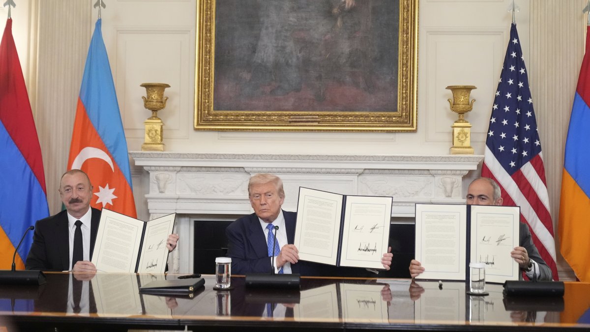 President Donald Trump (C), joined by Armenian Prime Minister Nikol Pashinyan (R), and Azerbaijan President Ilham Aliyev holds a signed trilateral agreement during a ceremony in the State Dining Room of the White House, in Washington DC, U.S.,  Aug. 8, 2025. (AP Photo)