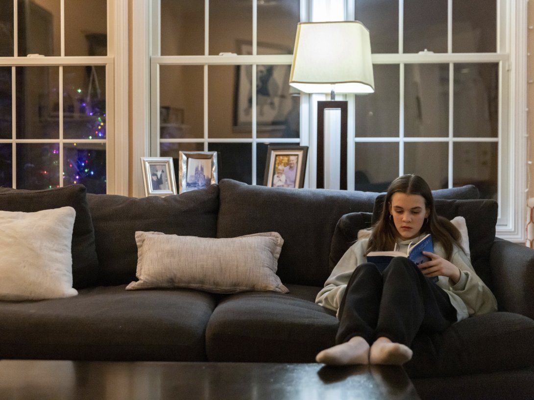 Teenager Sutton Bulkeley reads the novel &#039;Mockingjay&#039; by Suzanne Collins in the living room, in Westport, Connecticut, U.S., Feb. 16, 2024. (AP Photo)