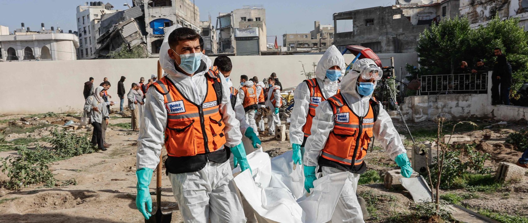 Civil defence personnel carry a body bag containing human remains after exhuming graves inside the Al-Ahli Arab Baptist Hospital to transfer the remains to official burial sites in Gaza City, Dec. 7, 2025. (AFP Photo)