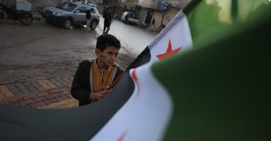 A child holds a flag amid celebrations in Tal Rifaat, which was cleansed from PKK/YPG terrorists, to mark the first anniversary of Bashar Assad&#039;s fall, in Tal Rifaat, Syria, Dec. 1, 2025. (AA Photo)