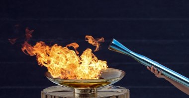 Actress Mary Mina in the role of a high priestess, lights the 2026 Milano-Cortina Winter Olympic torch during the handover ceremony at the Panathenaic Stadium, Athens, Greece, Dec. 4, 2025. (Reuters Photo)