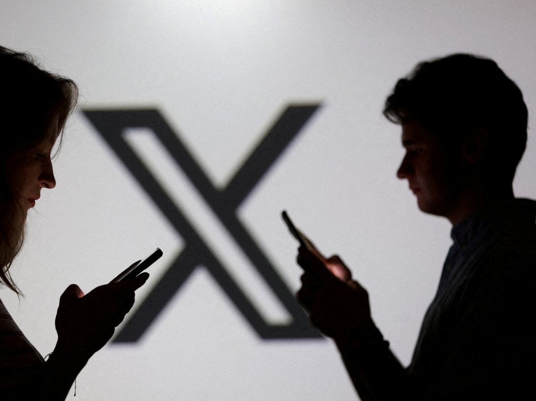 Teenagers pose for a photo while holding smartphones in front of an X logo in this illustration, Sept. 11, 2025. (Reuters Photo)