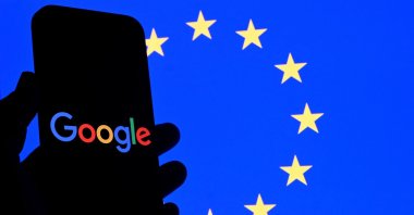 This illustration photograph shows the logo of Google displayed on a smartphone in front of an European Union flag in Brussels, Belgium, Sept. 29, 2025. (AFP Photo)