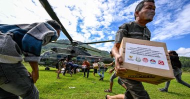 Residents carry supplies distributed by Indonesian air force personnel in flood-affected areas in Bener Meriah district, Aceh province, Indonesia, Dec. 4, 2025. (AFP Photo)