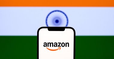 The e-commerce company Amazon logo is seen on a smartphone with the backdrop of India&#039;s national flag displayed on a screen ,n this illustration photo, New Delhi, India, Dec. 10, 2025. (AFP Photo) 