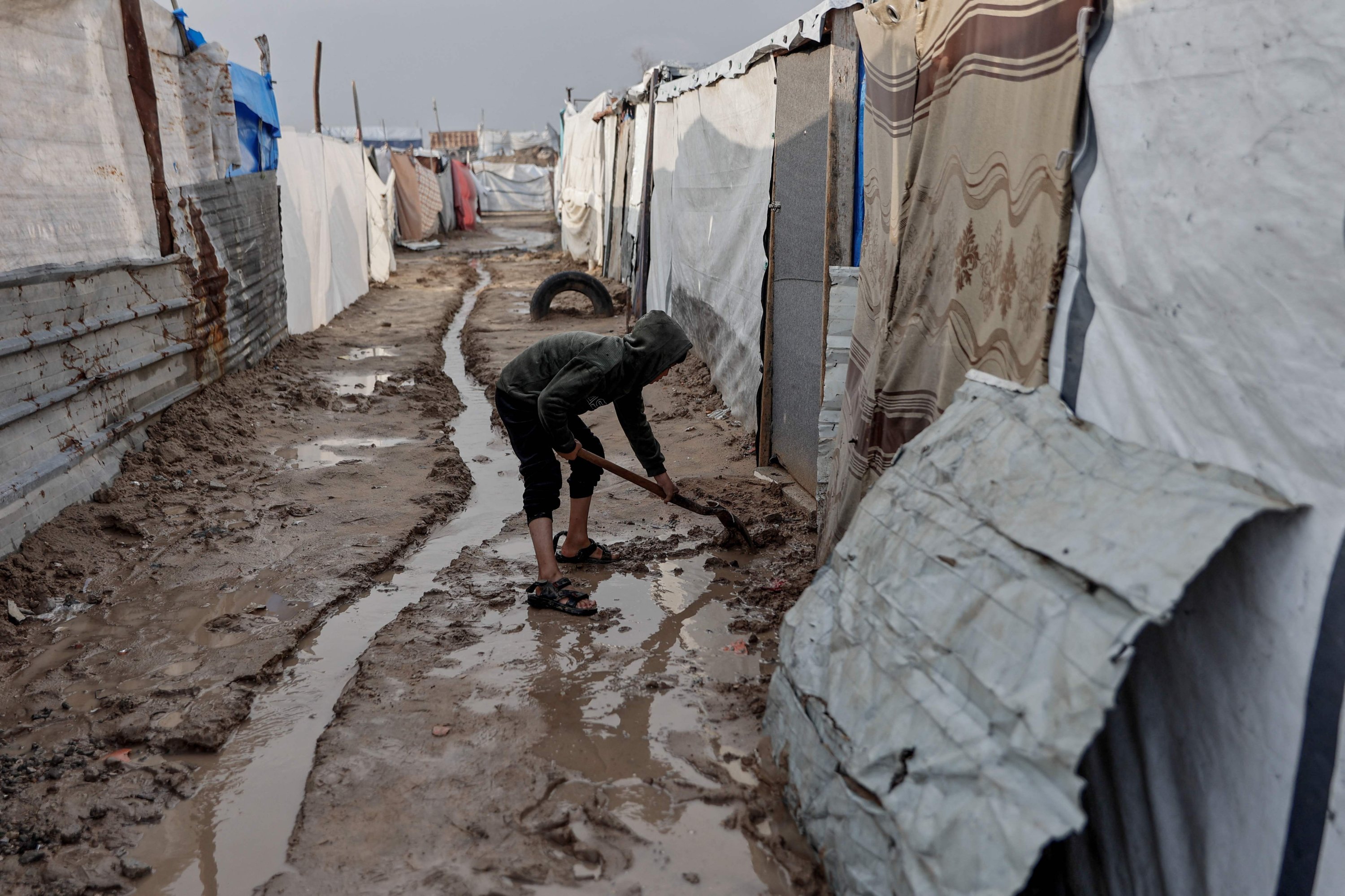 A boy reinforces his tent at a makeshift camp sheltering displaced Palestinians after heavy rains in the Zeitoun neighbourhood of Gaza City, Palestine, Dec. 11, 2025. (AFP Photo)