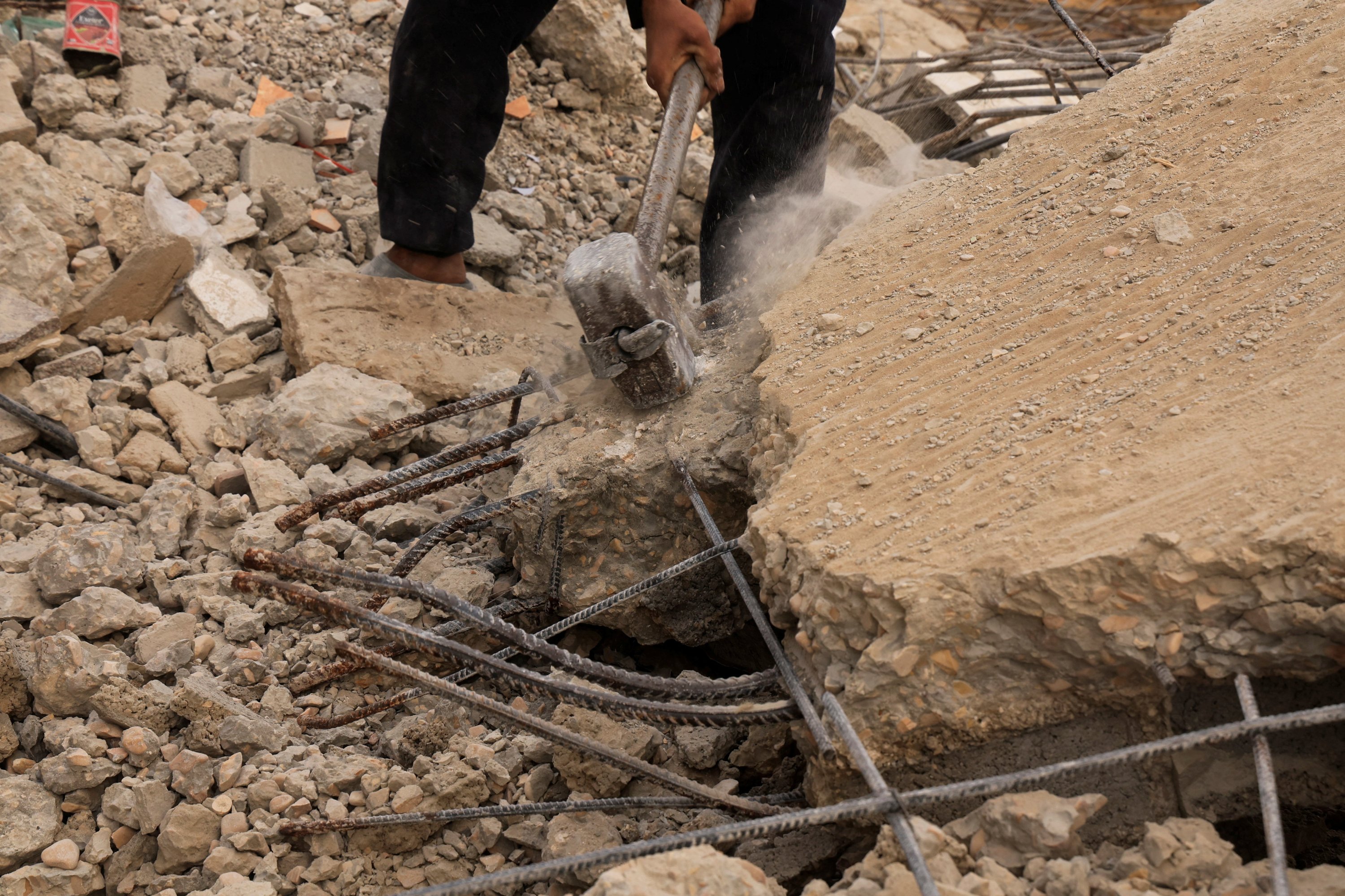 A Palestinian worker breaks concrete to extract steel bars from destroyed homes, using only simple hand tools amid a severe shortage of construction materials caused by long-standing restrictions on the entry of cement and iron, in Khan Younis, southern Gaza Strip, Palestine, Dec. 9, 2025. (Reuters Photo)