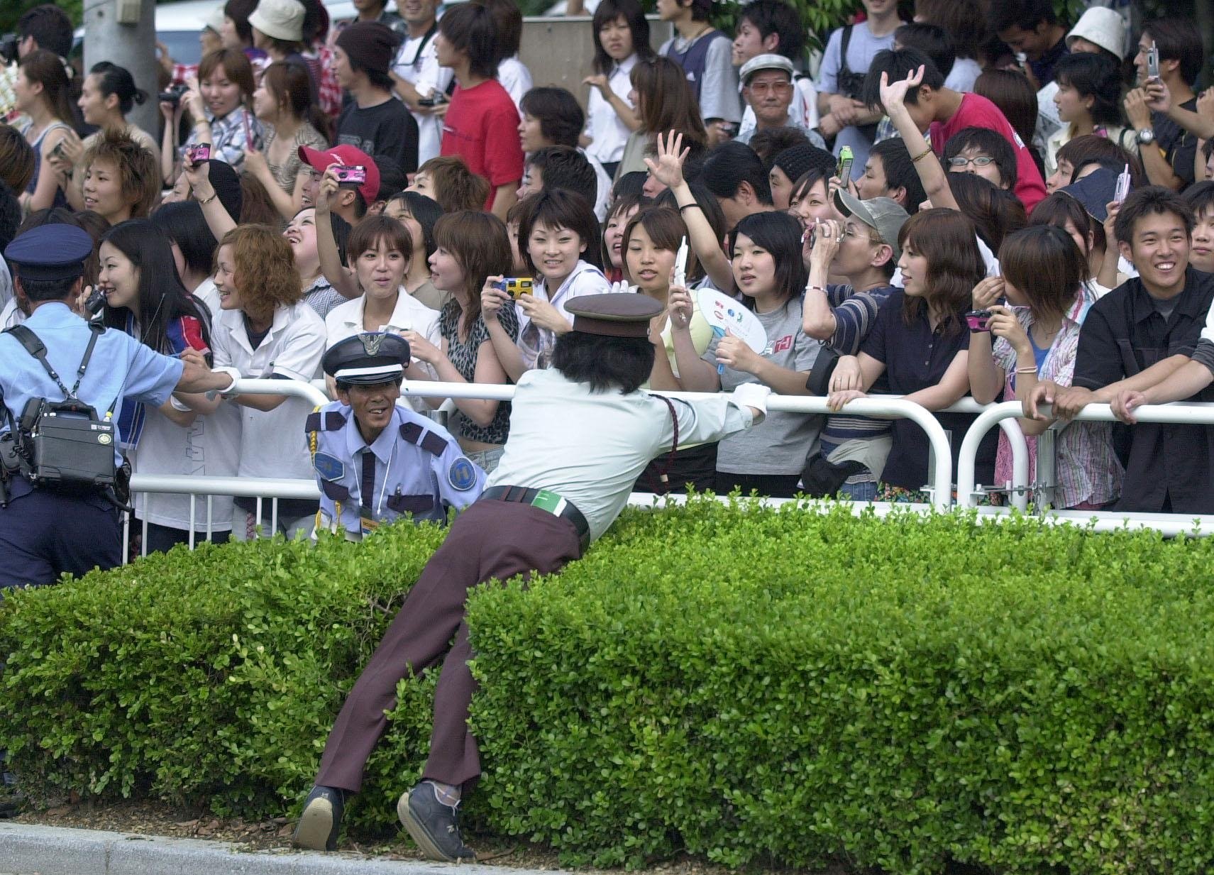 Japanese security guards keep screaming fans back from the England bus as they celebrate England's passage into the last 16 in the 2002 World Cup, Tokyo, Japan, June 12, 2002. (Getty Images Photo)