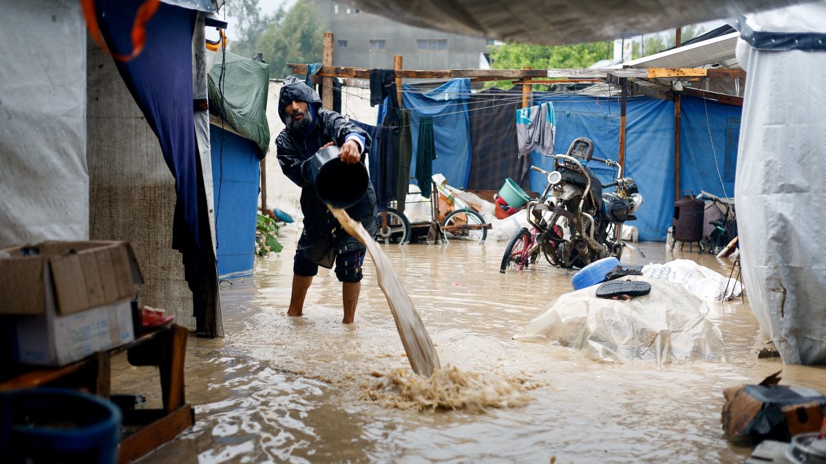 A displaced Palestinian man clears muddy water in a flooded tent camp on a rainy day in Nuseirat, Gaza Strip, Palestine, Dec. 12, 2025. (Reuters Photo)