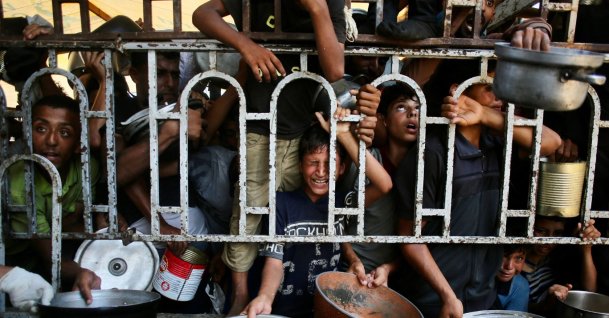 Palestinian children wait for a meal at a charity kitchen in the Mawasi area of Khan Younis in the southern Gaza Strip, July 22, 2025. (AFP File Photo)