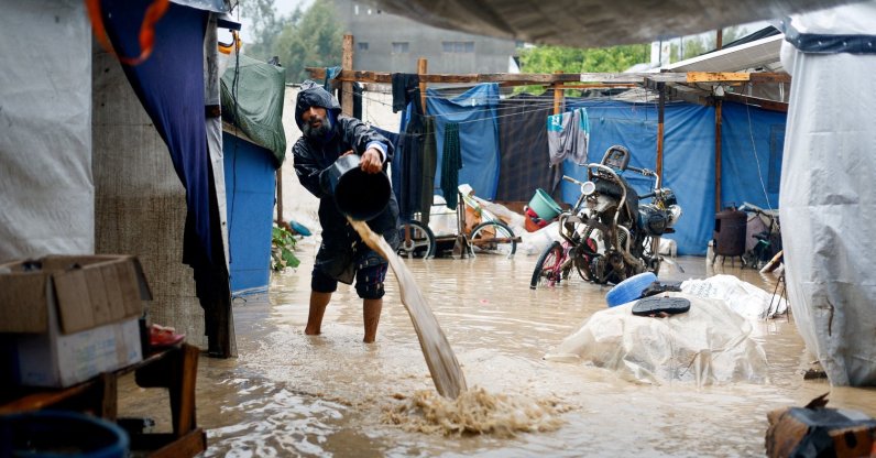 A displaced Palestinian man clears muddy water in a flooded tent camp on a rainy day, Nuseirat, Gaza Strip, Palestine, Dec. 12, 2025. (Reuters Photo)