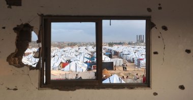 People stand outside a "tent city" housing displaced Palestinians who lost their homes in the Gaza war, following heavy rains in the Nuseirat refugee camp, Gaza Strip, Palestine, Dec. 13, 2025. (AFP Photo)