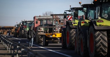 A man walks past tractors blocking access to the A64 motorway, Carbonne, southwestern France, Dec. 13, 2025. (AFP Photo)